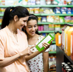 Happy mother and daughter reading product information while shopping at supermarket